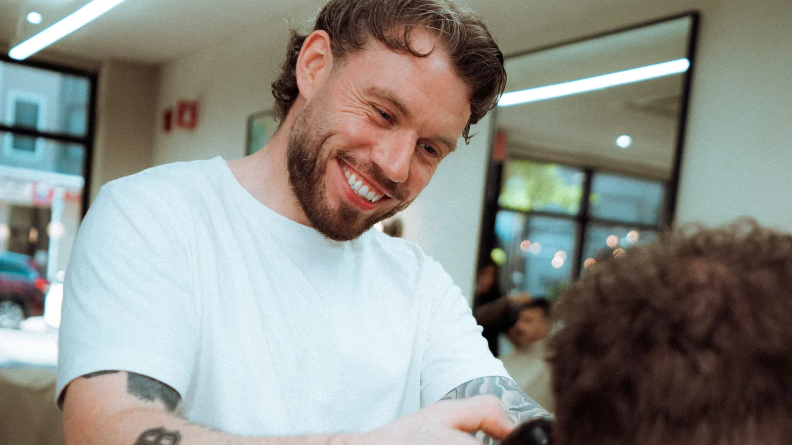 Niall laughing with a client mid-cut in the Somerville shop